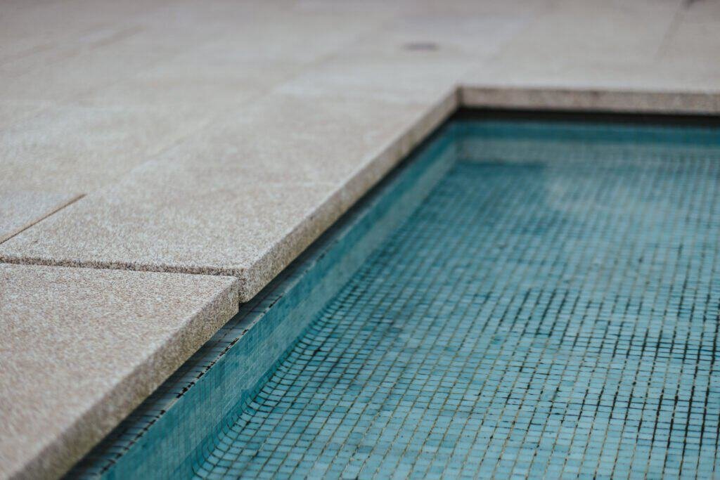Pool edge with tiled interior and concrete deck.