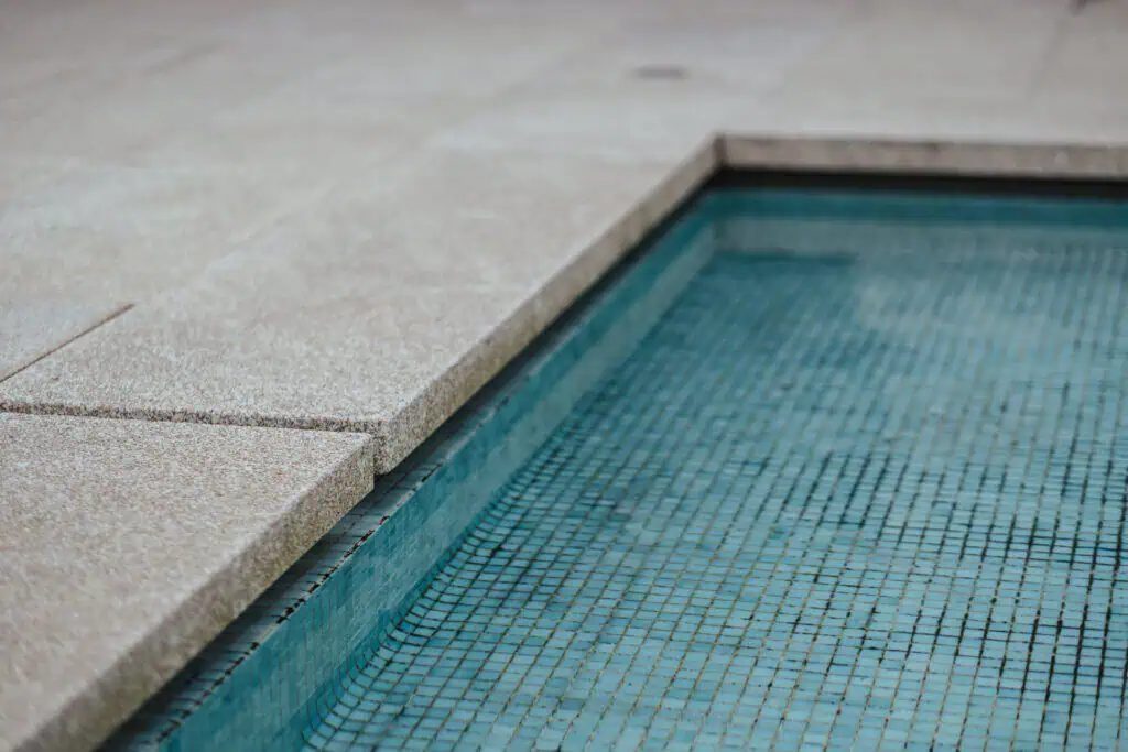 Pool edge with tiled interior and concrete deck.