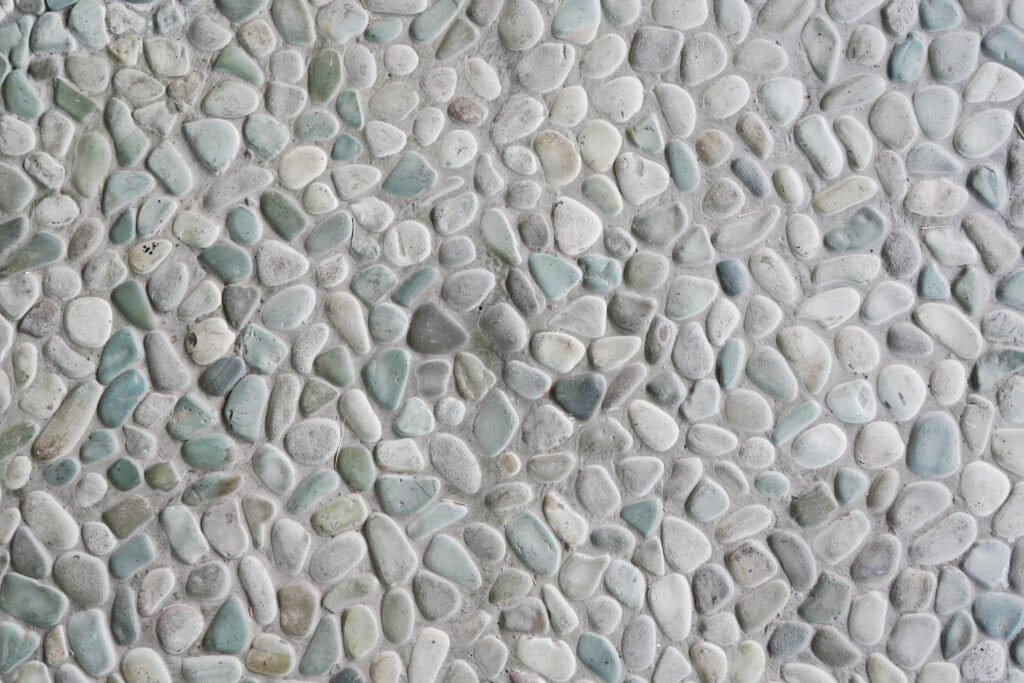 Natural stone pebble pool deck surface for outdoor swimming pools.