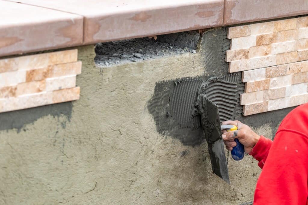 Pool wall construction with waterproofing and tiling in progress.